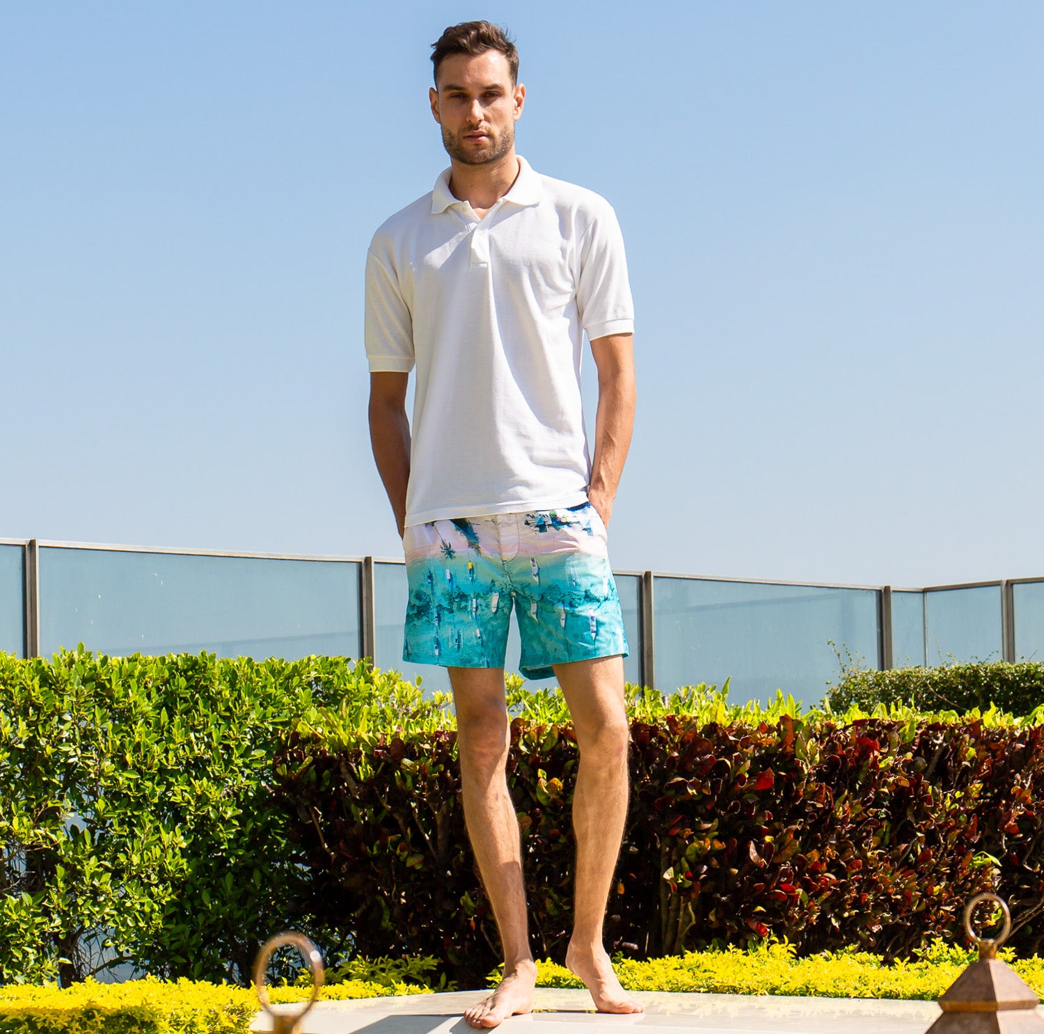 Model wearing Rwenzori swim shorts Bali Boats at a luxury villa rooftop in Bali with white polo short.
