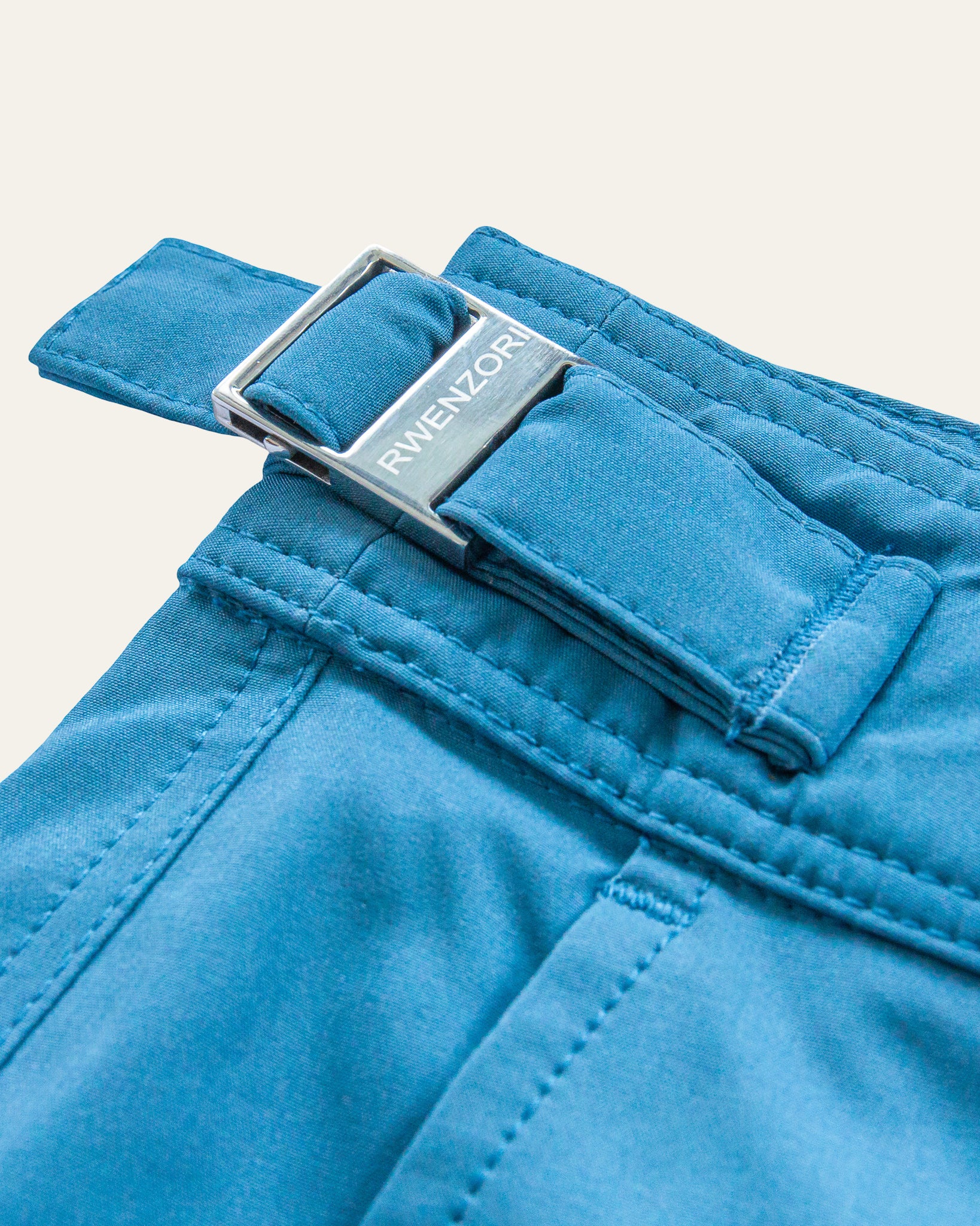RWENZORI performance series swim shorts in Mykonos Blue showcasing the detailed pocket and engraved polished stainless steel side buckles.