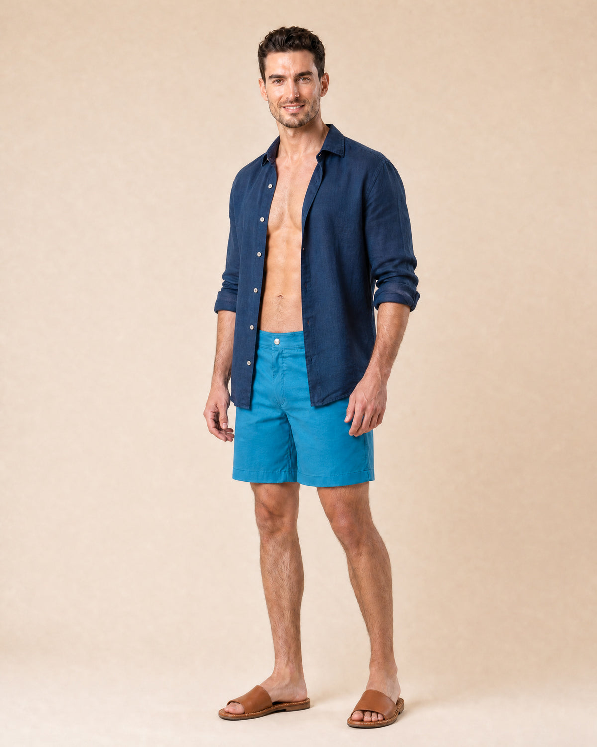 Man wearing RWENZORI Mykonos Blue Performance Series swim shorts with an open navy linen resort shirt.