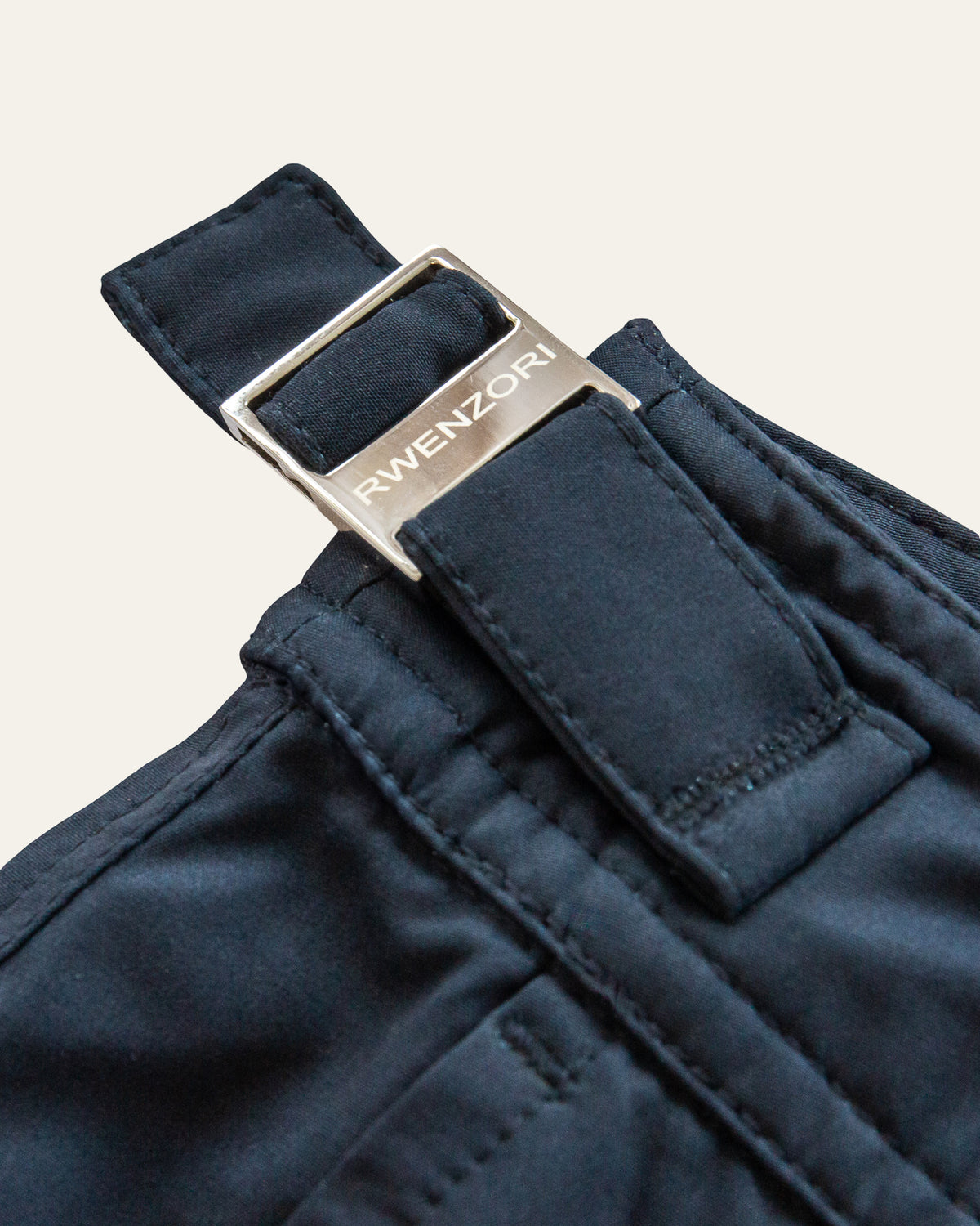 Close-up of the stainless steel buckle hardware on RWENZORI Nautic Navy Performance Series swim shorts.