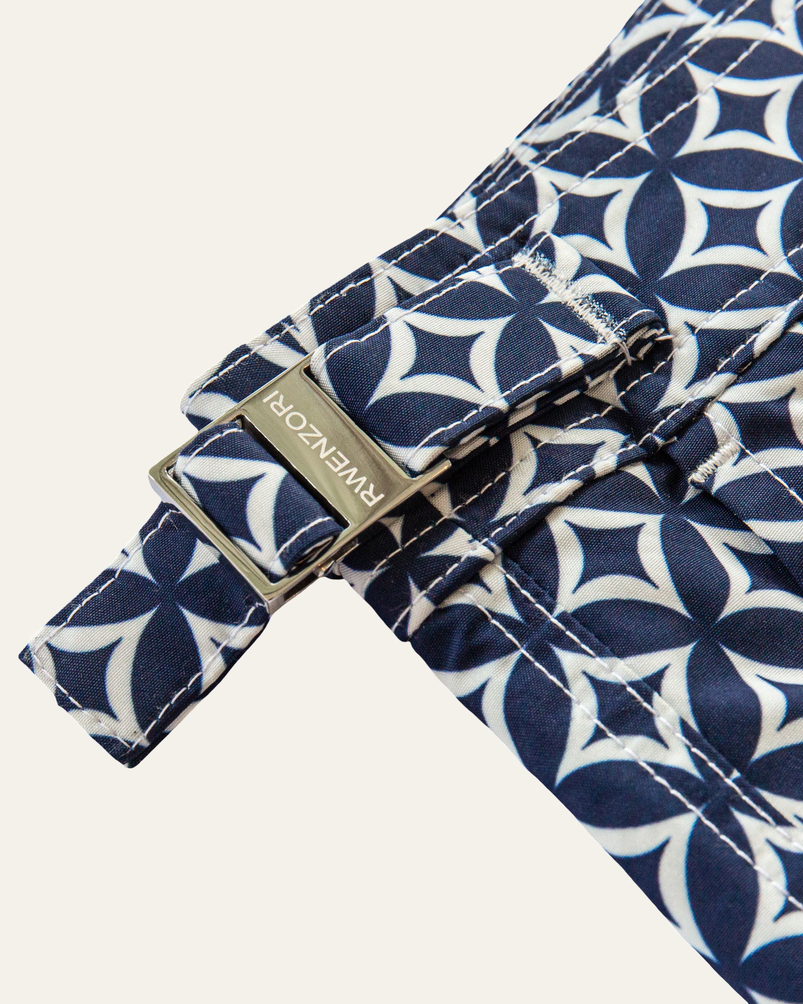 Close-up of the stainless steel buckle hardware on RWENZORI Palladio Venezia diamond print swim shorts.