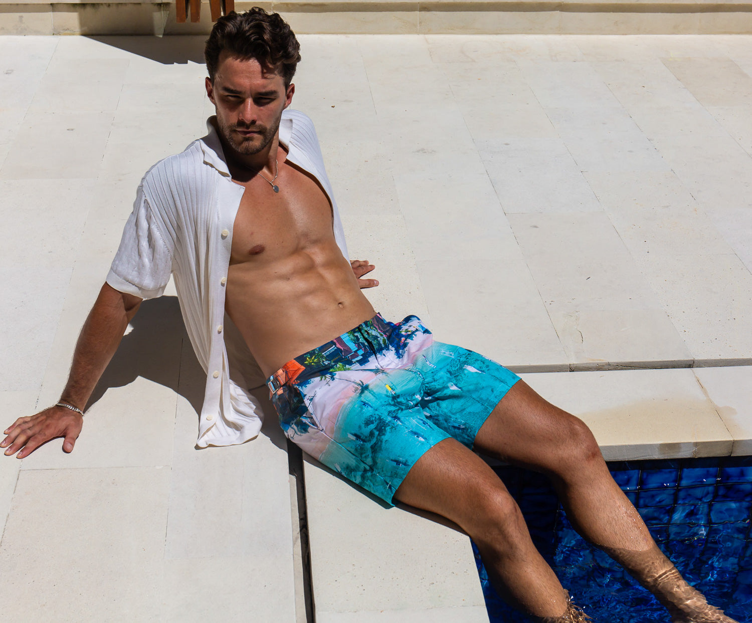 Model wearing Rwenzori swim shorts Bali Boats at a luxury villa pool in Bali.