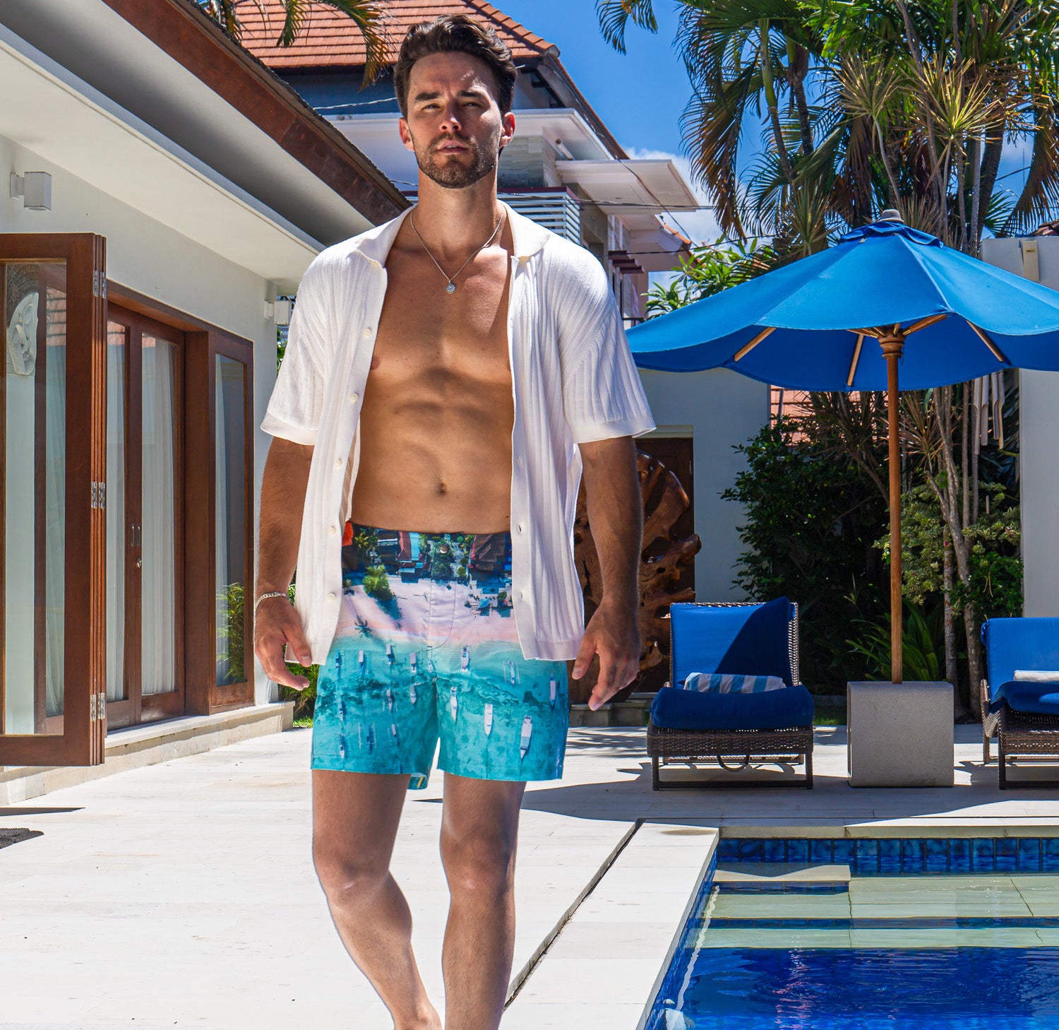 Model wearing Rwenzori swim shorts Bali Boats at a luxury villa pool in Bali showcasing quick dry comfort and mid-length design.