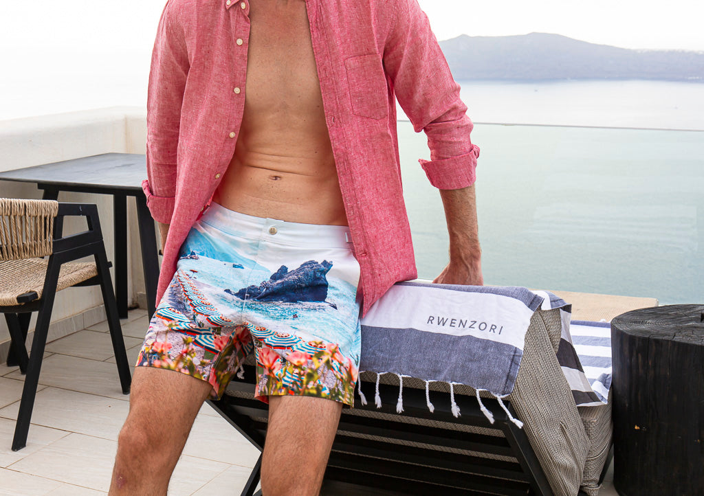 Rwenzori Cinque Terre men’s swim shorts styled with Turkish Peshtemal towel by the coast.