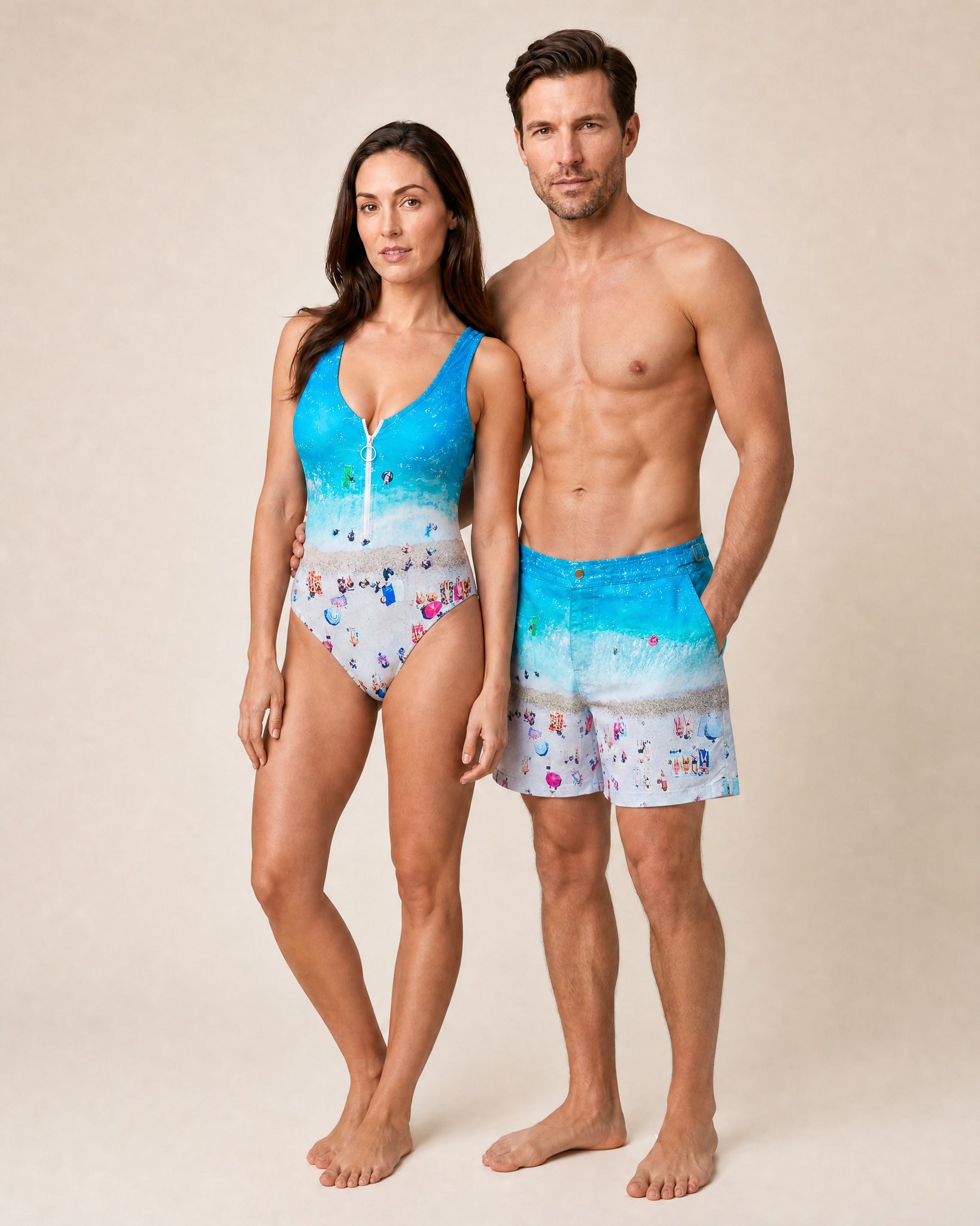 Couple in matching RWENZORI swimwear, front view — she wears the French Riviera print MATCH HIM one-piece swimsuit.