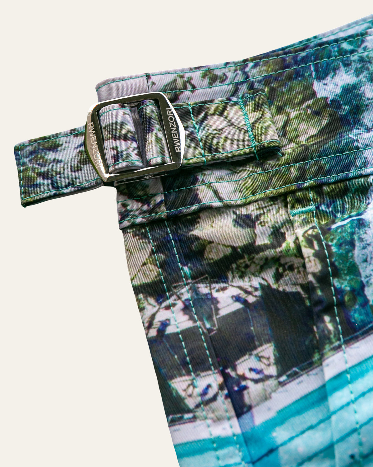 Close-up of the stainless steel buckle hardware on RWENZORI Bondi photo print swim shorts.