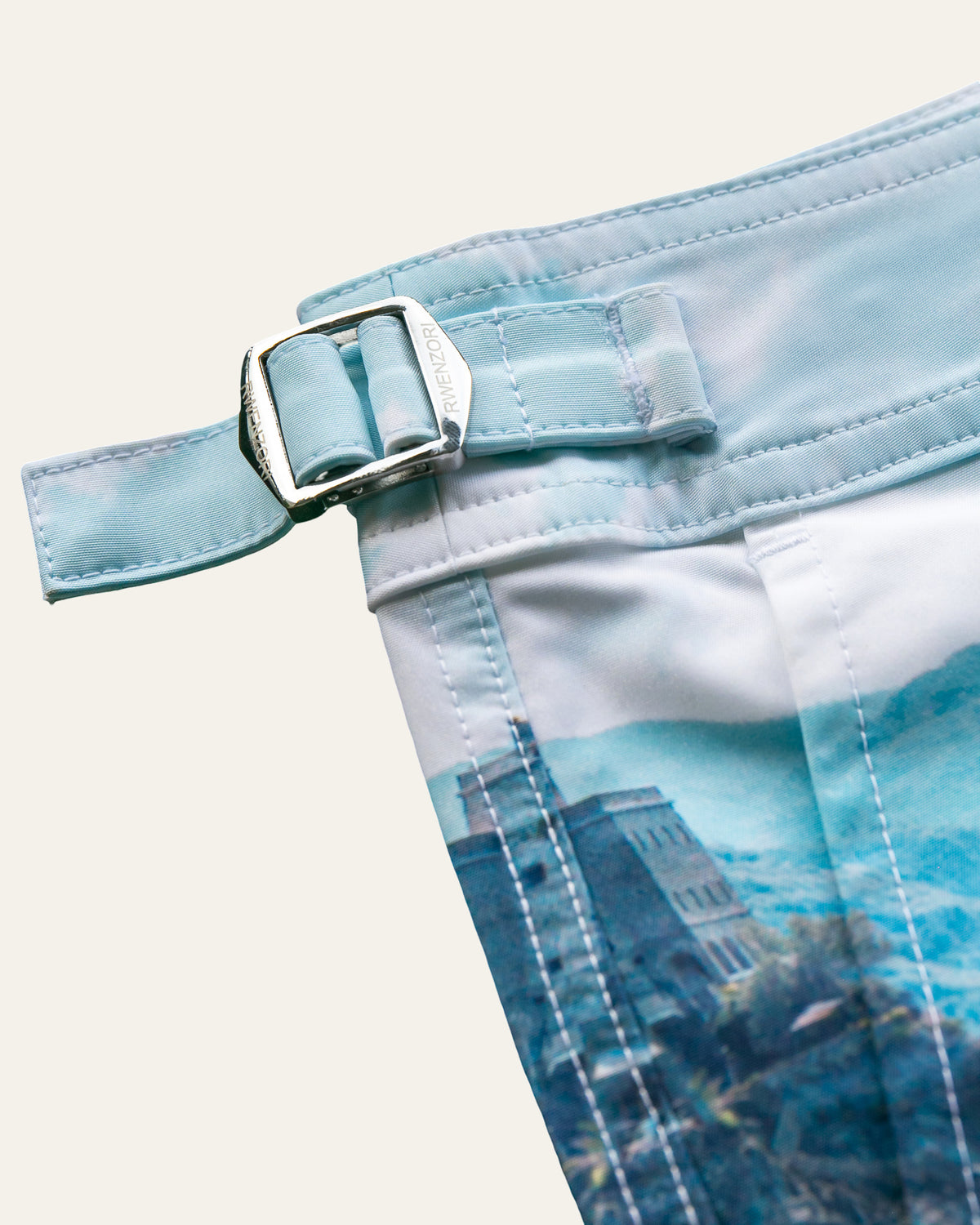 Close-up of the stainless steel buckle hardware on RWENZORI Cinque Terre photo print swim shorts.