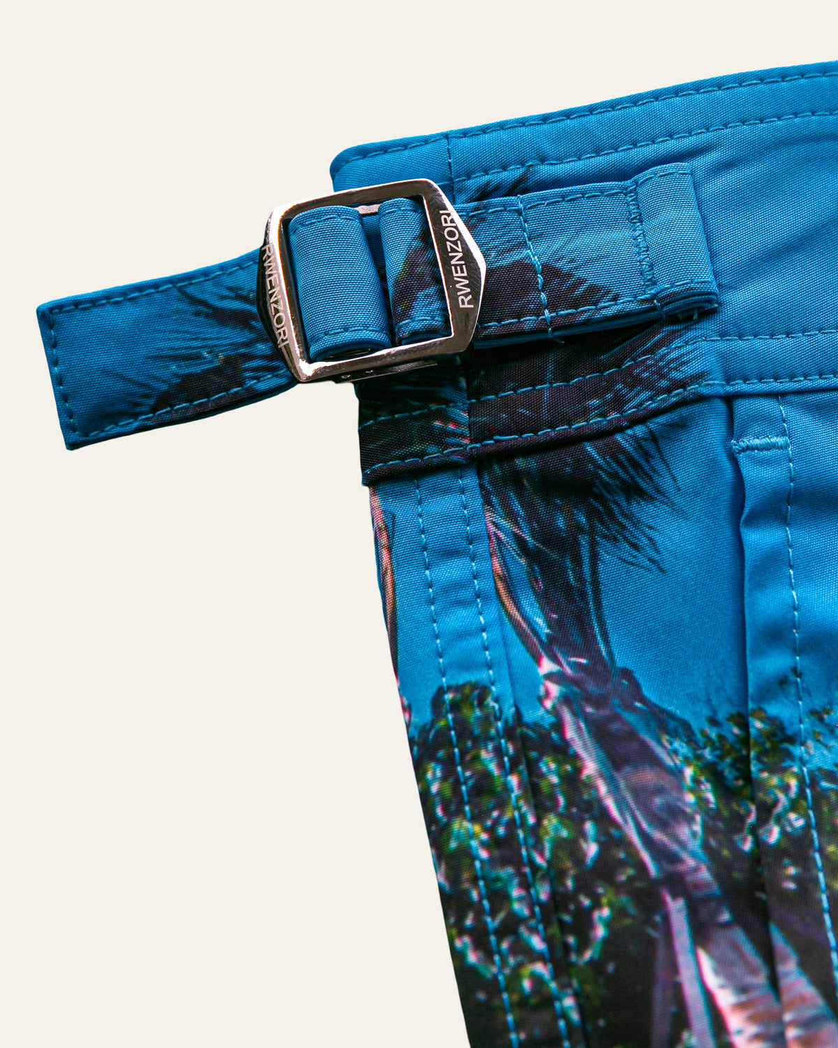 Close-up of the stainless steel buckle hardware on RWENZORI Flamingos photo print swim shorts.