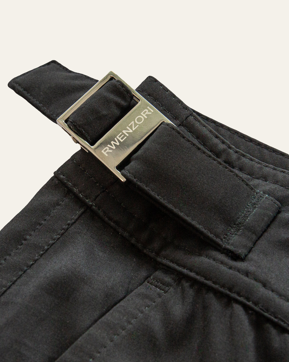 Close-up of the stainless steel buckle hardware on RWENZORI Jet Black Performance Series swim shorts.