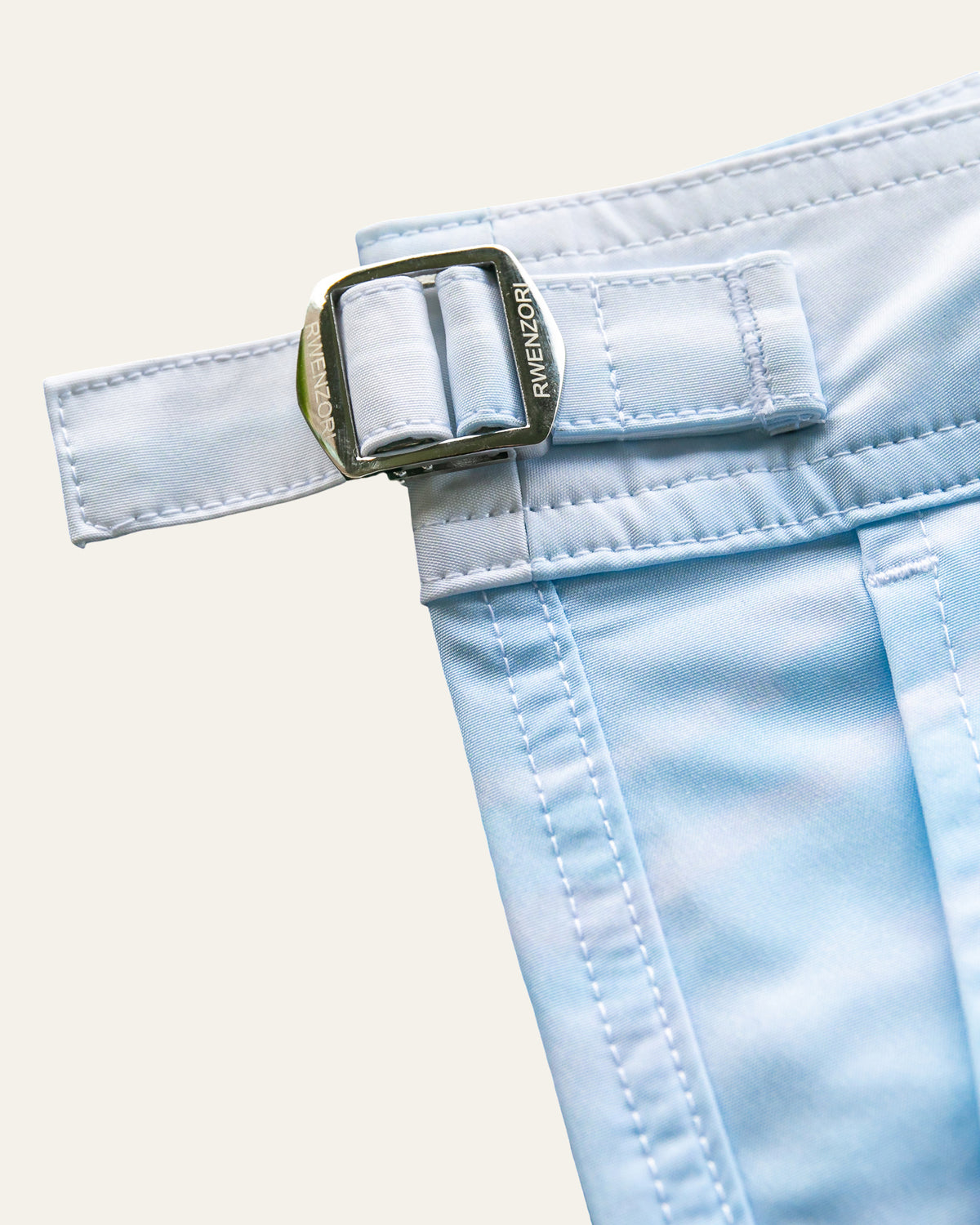 Close-up of the stainless steel buckle hardware on RWENZORI St Tropez photo print swim shorts.