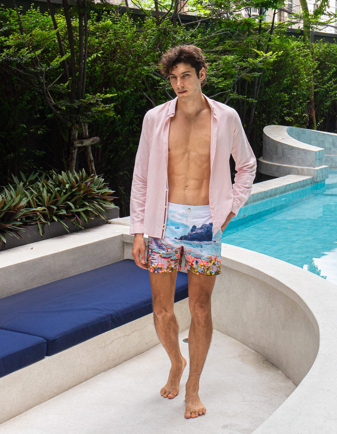 Model wearing Rwenzori Cinque Terre men’s swim shorts at Italian-style villa by pool and lounge Italy showcasing the ultimate resort wear shorts.
