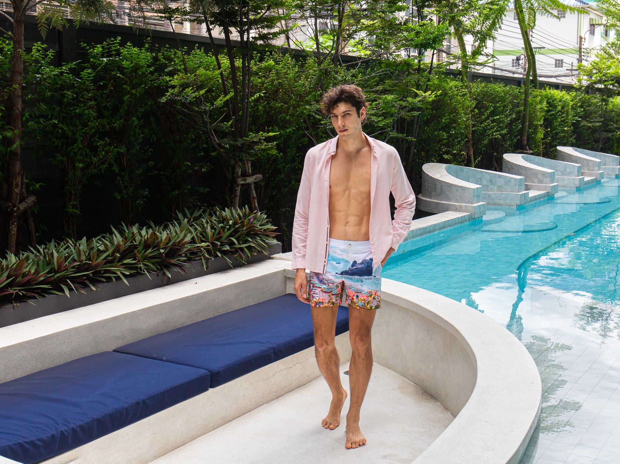 Model wearing Rwenzori Cinque Terre men’s swim shorts at Italian-style villa by pool and lounge Italy showcasing the ultimate resort wear shorts.
