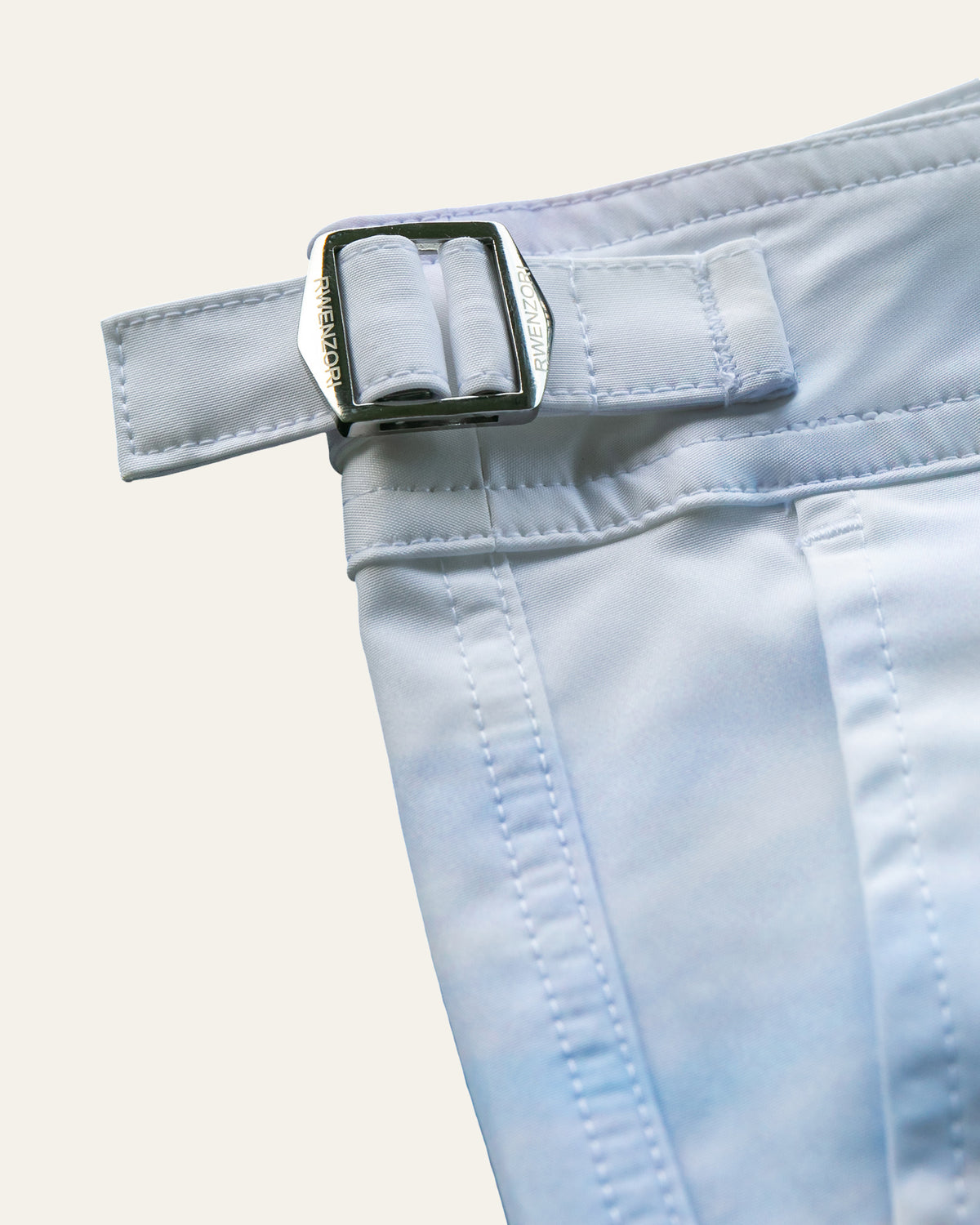 Close-up of the stainless steel buckle hardware on RWENZORI Venice Beach photo print swim shorts.