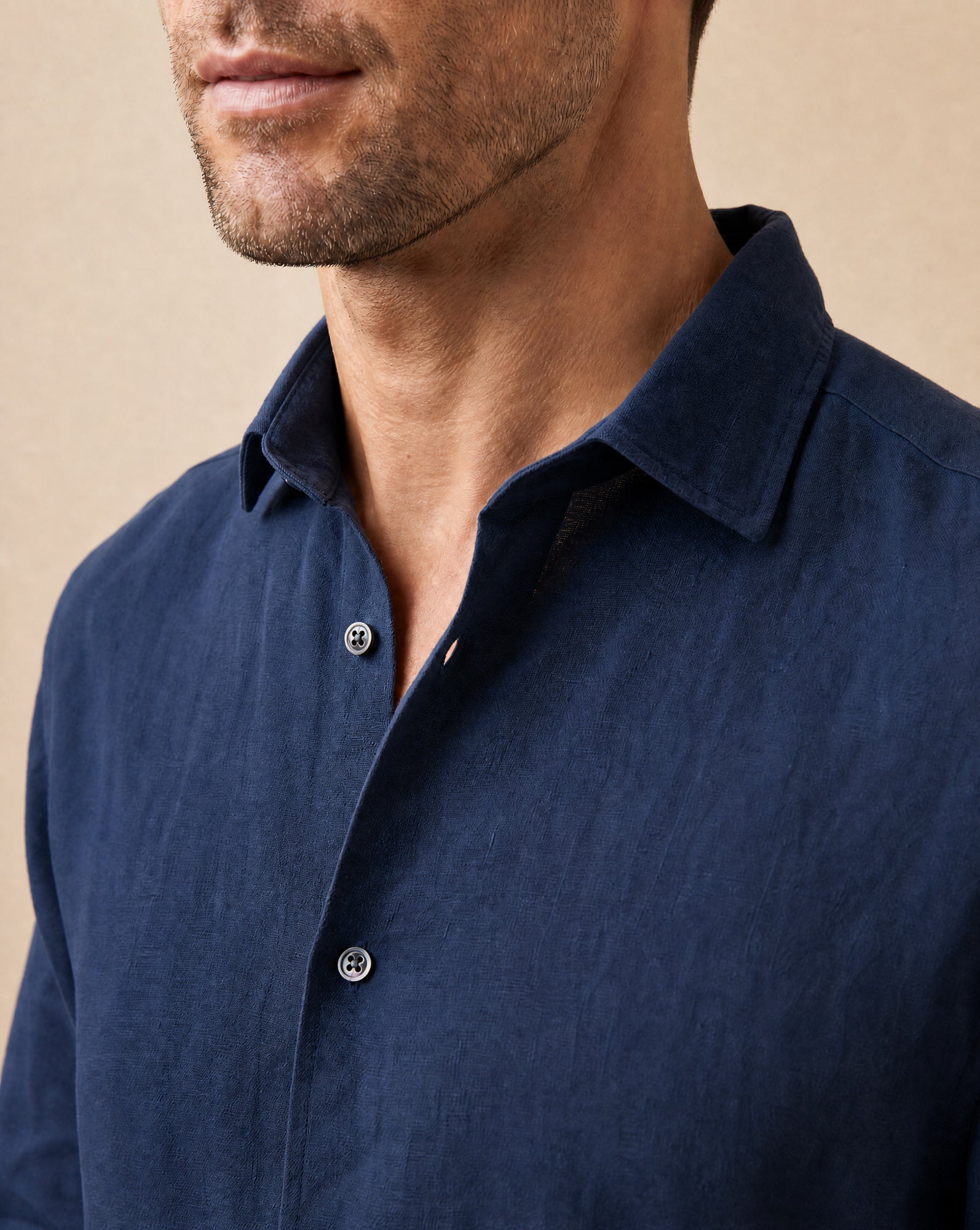 Close-up of collar and mother of pearl button detail on Rwenzori  men's navy linen shirt.