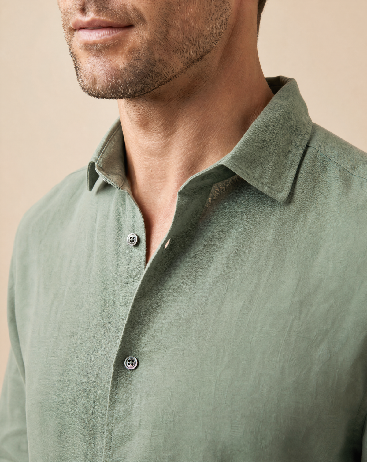 Close-up of collar and mother of pearl button detail on Rwenzori men's sage linen shirt.