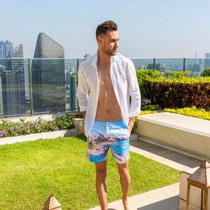 Model walking through villa garden wearing Rwenzori Waikiki men’s swim shorts in tropical print